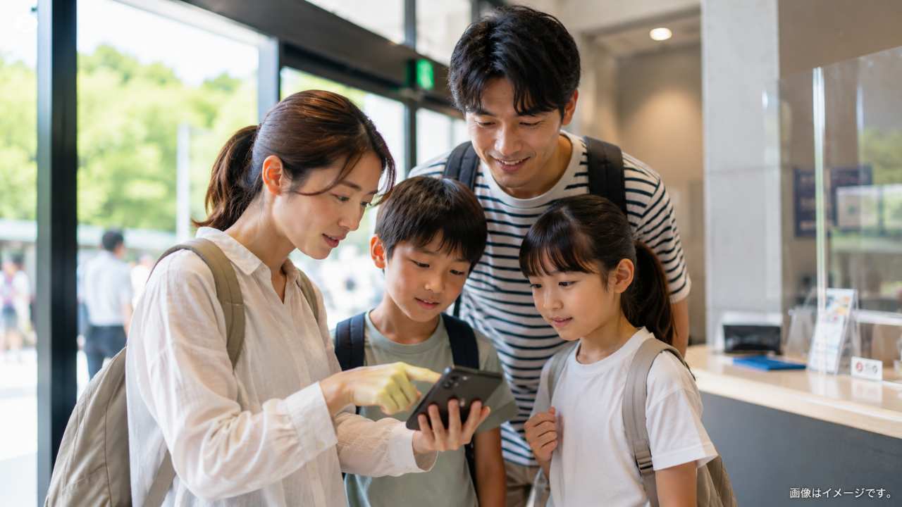 スマートフォンのクーポン画面と複数の入館券を見比べる家族